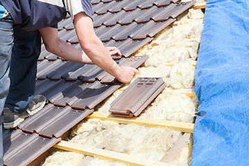 Image showing a roofer laying tile on the roof