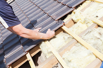 Image showing a roofer laying tile on the roof