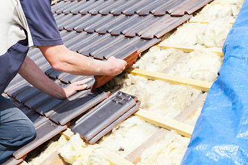 Image showing a roofer laying tile on the roof