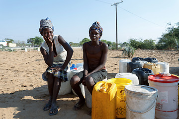 Image showing Unidentified Namibian woman with child near public tank with dri