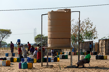 Image showing Unidentified Namibian woman with child near public tank with dri