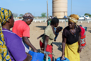 Image showing Unidentified Namibian woman with child near public tank with dri