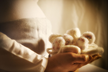 Image showing Pregnant woman is holding baby shoes