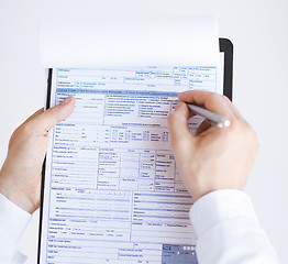 Image showing male doctor holding prescription paper in hand