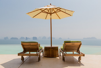 Image showing infinity pool with parasol and sun beds at seaside