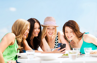 Image showing girls looking at smartphone in cafe on the beach