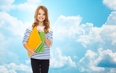 Image showing happy girl holding colorful folders over blue sky