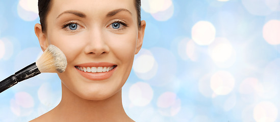 Image showing happy woman applying powder foundation with brush