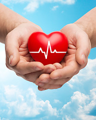 Image showing close up of hands holding heart with cardiogram