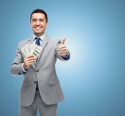 Image showing smiling businessman with money showing thumbs up