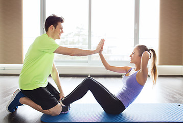 Image showing woman with personal trainer doing sit ups in gym