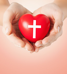 Image showing close up of hands holding heart with cross symbol