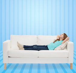 Image showing smiling little girl lying on sofa and dreaming