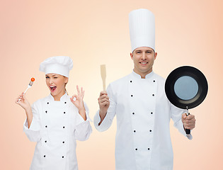 Image showing happy chefs or cooks couple with kitchenware