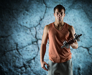 Image showing young man with dumbbell flexing biceps