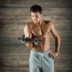 Image showing young man with dumbbell flexing biceps