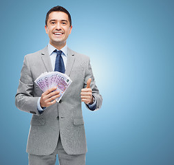 Image showing smiling businessman with money showing thumbs up