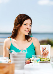 Image showing girl eating in cafe on the beach