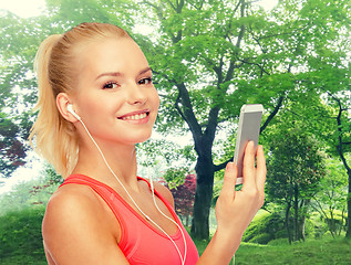 Image showing smiling sporty woman with smartphone and earphones