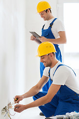 Image showing builders with tablet pc and fixing wiring indoors