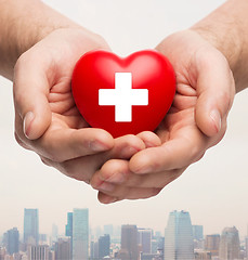 Image showing male hands holding red heart with white cross