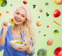 Image showing smiling young woman eating green vegetable salad