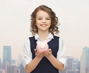 Image showing happy girl holding piggy bank on palms