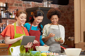 Image showing happy women with tablet pc cooking in kitchen