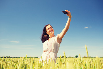 Image showing smiling girl with smartphone on cereal field