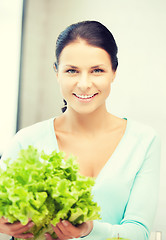 Image showing woman in the kitchen with green salad leaves