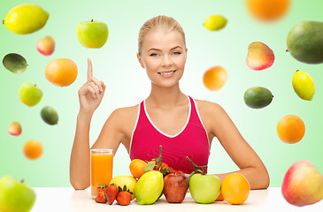 Image showing woman with juice and fruits pointing finger up