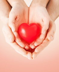 Image showing close up of couple hands holding red heart