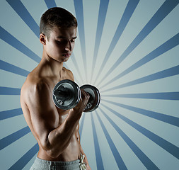 Image showing young man with dumbbell flexing biceps