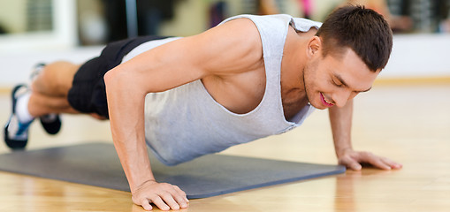 Image showing smiling man doing push-ups in the gym