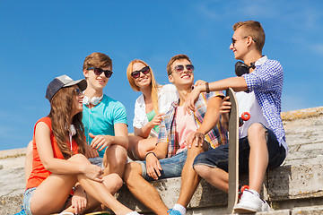 Image showing group of smiling friends sitting on city street