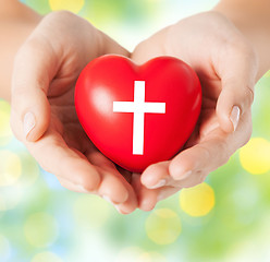 Image showing close up of hands holding heart with cross symbol