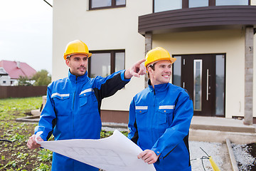 Image showing smiling builders with blueprint pointing finger