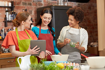 Image showing happy women with tablet pc cooking in kitchen