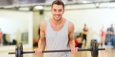 Image showing smiling man with barbell in gym
