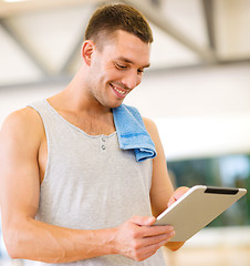 Image showing young man with tablet pc computer and towel in gym