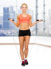 Image showing smiling sporty woman jumping  with skipping rope