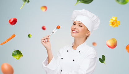 Image showing smiling female chef with fork and tomato