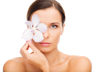 Image showing relaxed woman with orchid flower over eye