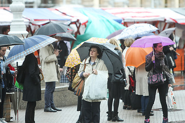 Image showing People with umbrellas on square