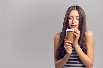 Image showing Woman drinking hot drink from disposable paper cup