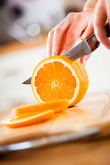 Image showing Woman\'s hands cutting orange