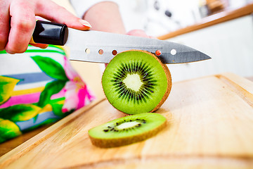 Image showing Woman\'s hands cutting kiwi