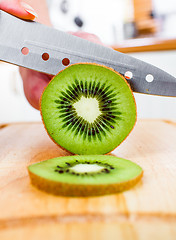 Image showing Woman\'s hands cutting kiwi