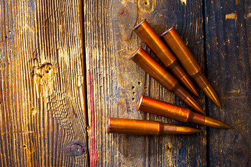 Image showing five rifle cartridges on wooden surface