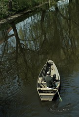 Image showing Man and dog  in boat on river